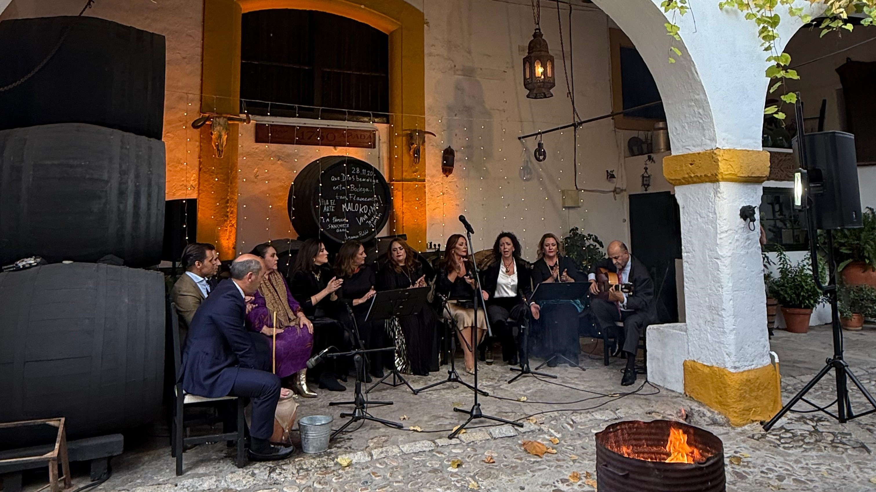 Seis cantantes y un guitarrista actuando en un patio andaluz
